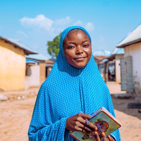 Fauziya, a student from Nigeria, standing in front of her home 