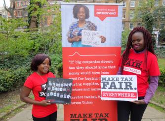 Two women holding posters calling for fair taxation