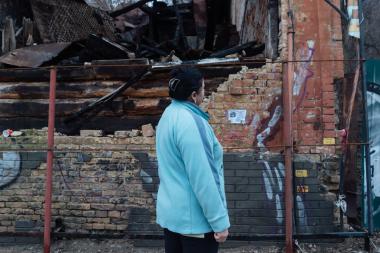 Liza (not her real name), a volunteer at Insight NGO an ActionAid partner photographed in front of a burned house in Kyiv